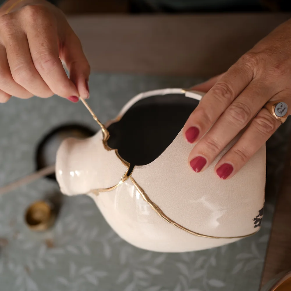Rachel van der Schaaf applying gold to a repaired bottle  in her Kintsugi studio