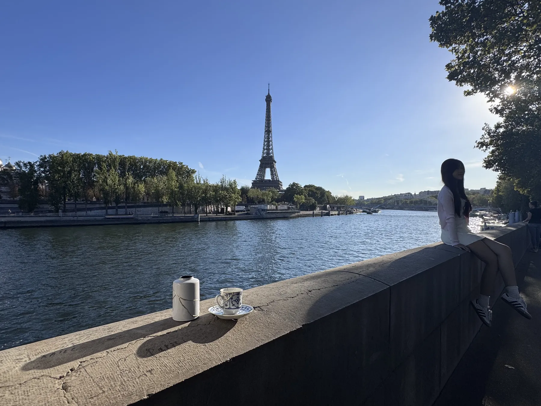 kintsugi-parijs-eiffeltoren-vaas-kopje Kintsugi vaas en kopje met gouden breuklijnen op een muurtje langs de Seine, met de Eiffeltoren op de achtergrond