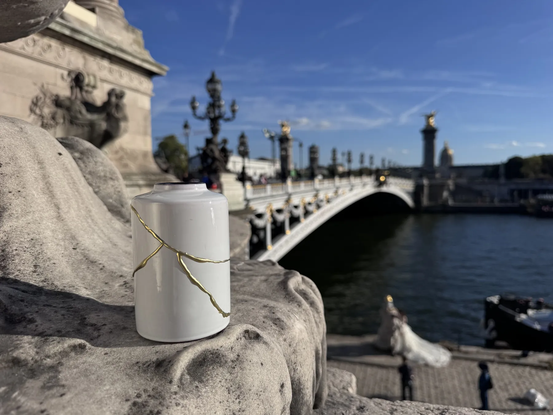 Witte Kintsugi vaas op een muurtje met de Pont Alexandre III op de achtergrond Witte Kintsugi vaas op een muurtje met de Pont Alexandre III op de achtergrond