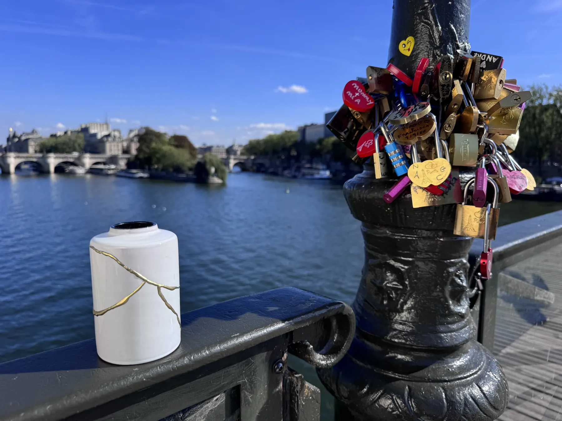 Witte Kintsugi vaas op de reling van een brug met slotjes boven de Seine Witte Kintsugi vaas op de reling van een brug met slotjes boven de Seine