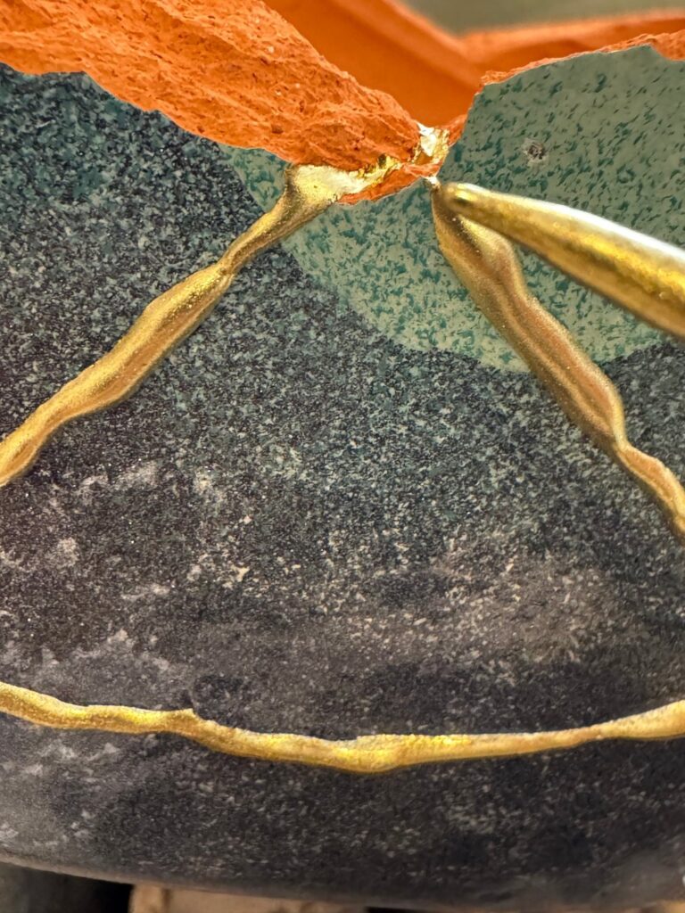 Een gebroken kom van terracotta met gouden lijnen die de scherven met elkaar verbinden